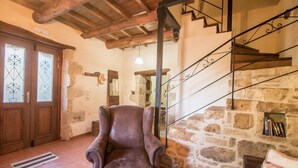 A rustic interior with a stone fireplace, wooden beams, and a leather armchair. - Villa Kourkoulios in Apokoronos (Apokoronas)