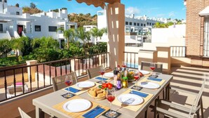 A dining table set for a meal with a view of the surrounding buildings and greenery. - Casa Eva in Nerja With 3 Bedrooms and 3 Bathrooms (Nerja)