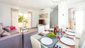 A modern living room with a dining area, large windows, and a staircase leading to an upper floor. - Casa Eva in Nerja With 3 Bedrooms and 3 Bathrooms (Nerja)
