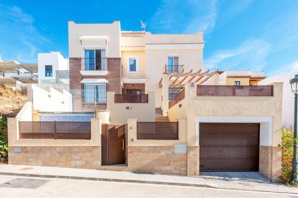 A modern two-story house with a garage, a balcony, and a small outdoor area with a fence. - Casa Eva in Nerja With 3 Bedrooms and 3 Bathrooms (Nerja)