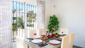 A dining area with a glass table, white chairs, and a view of greenery outside. - Casa Eva in Nerja With 3 Bedrooms and 3 Bathrooms (Nerja)