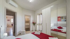 Ein modernes Schlafzimmer mit einem großen Bett, einem begehbaren Kleiderschrank und einem durch eine offene Tür einsehbaren Badezimmer.