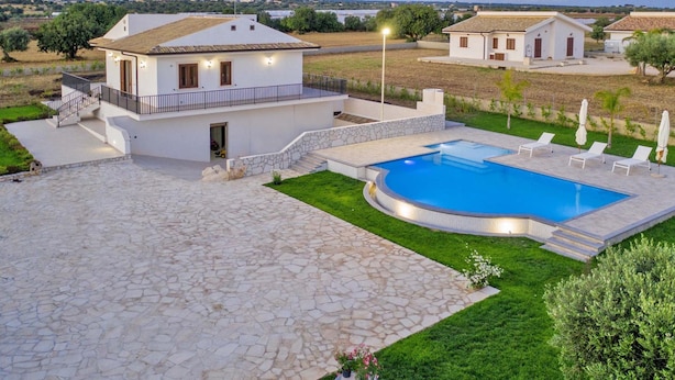 Eine moderne Villa mit Schwimmbad, Stein-Terrasse und Blick auf die Landschaft.