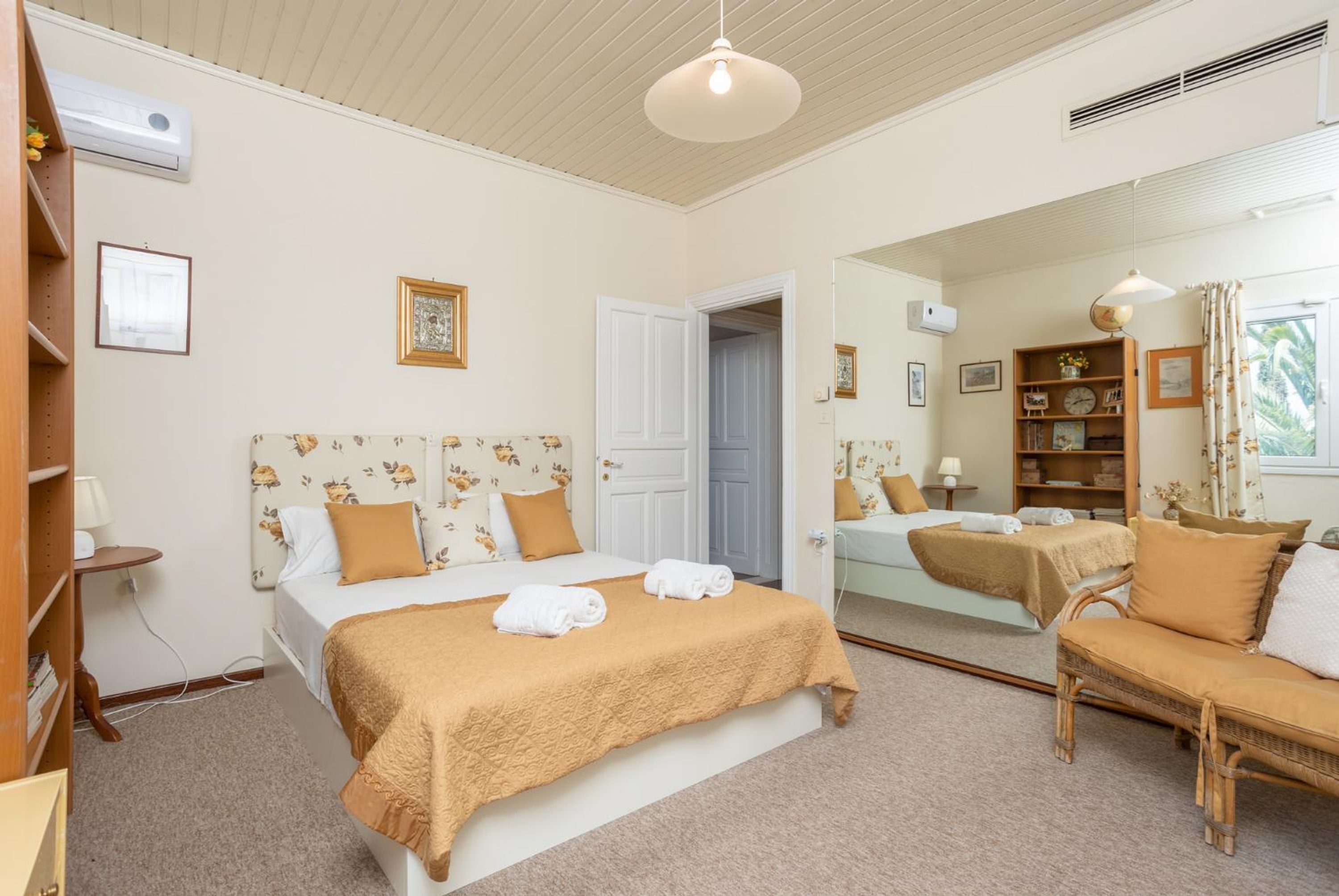 A bedroom with a large bed, a bedside table, a mirror, and a wardrobe.