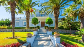 A grand entrance with a stone staircase leading to a white building with blue shutters and a balcony.