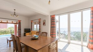 A spacious dining area with a wooden table, chairs, and a TV. - Villa Eleni Agios Stephanos (Corfu)