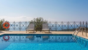 A swimming pool with a view of the sea, two lounge chairs, and a lifebuoy. - Villa Eleni Agios Stephanos (Corfu)