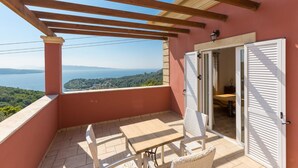 A balcony with a view of the sea, a table, and chairs. - Villa Eleni Agios Stephanos (Corfu)