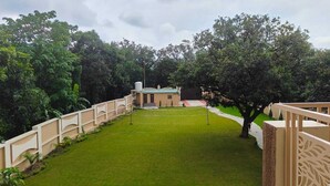 A courtyard with a small building, surrounded by a fence and trees. - Atithi Stays (Ramnagar)