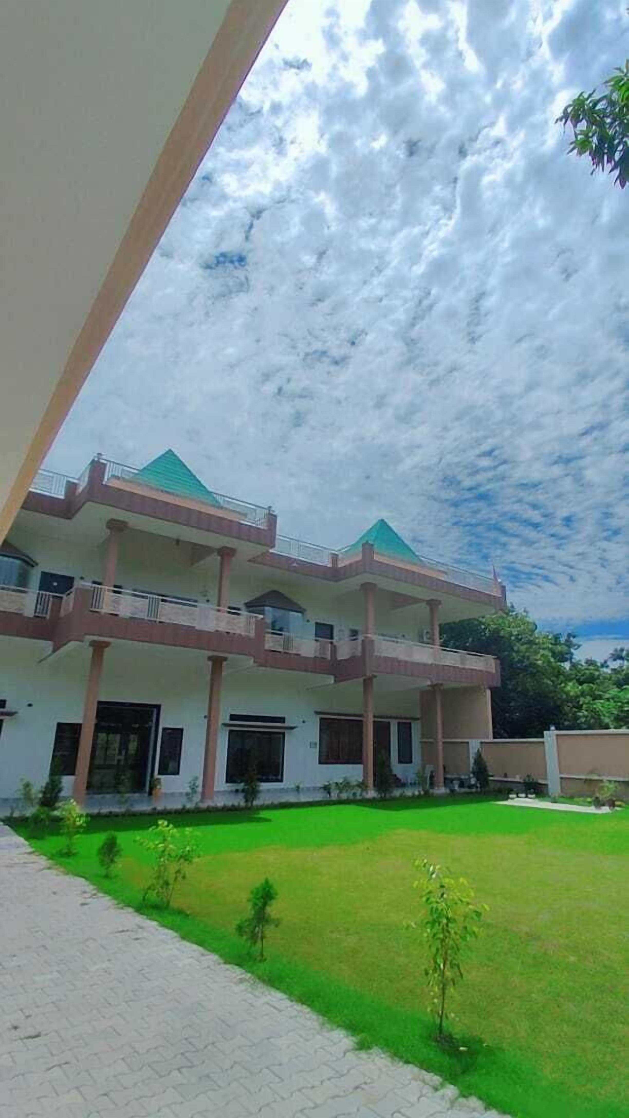Un edificio a più piani con un tetto verde, una zona esterna coperta e un prato curato.