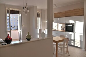 Una cocina moderna con armarios blancos, encimera de madera y un comedor con sillas blancas.