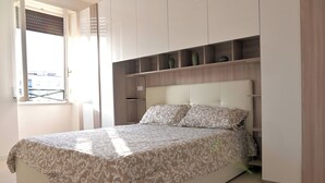 A bedroom with a bed, built-in shelving, and a window with blinds. - Emerenziana Lovely Apartment (Rome)