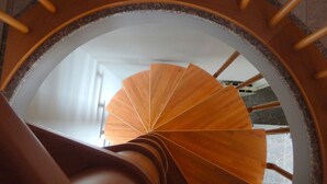 Un escalier en colimaçon avec une rampe en bois et un motif circulaire sur le mur.