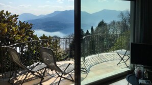 Un balcon avec vue sur les montagnes et un lac. On y trouve deux chaises et une table.