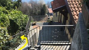 Un escalier en pierre avec des rampes métalliques menant à un bâtiment doté d’un toit en tuiles.