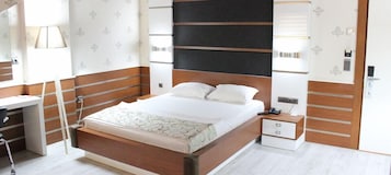 Un dormitorio moderno con estructura de cama de madera, una mesita de noche con lámpara y un escritorio con silla.