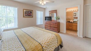 A bedroom with a bed, dresser, TV, and a ceiling fan. - Book Now! Disney and Theme Parks Days, Poolside Family Villa Awaits! (Davenport)