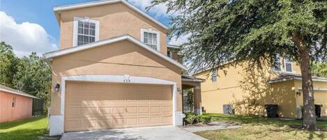 A two-story house with a beige exterior, a garage number 339, and a tree in the front yard.