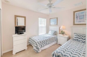 A bedroom with two beds, a TV on a dresser, a ceiling fan, and a window with blinds. - Luxurious 4-bedroom Apartment With Private Pool in Davenport (Davenport)