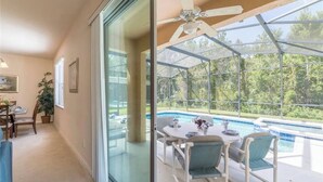 A room with a glass door leading to a pool area. - Book Now! Disney and Theme Parks Days, Poolside Family Villa Awaits! (Davenport)