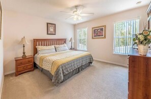 A bedroom with a bed, bedside tables, a ceiling fan, and two windows with blinds. - Luxurious 4-bedroom Apartment With Private Pool in Davenport (Davenport)