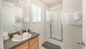 Een badkamer met een wastafel, spiegel, badkamermeubel en douche.
