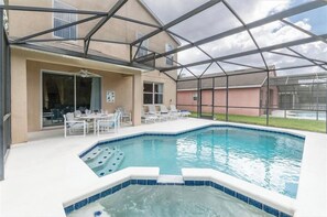 A covered outdoor swimming pool with lounge chairs and a table, surrounded by a glass enclosure. - Luxurious 4-bedroom Apartment With Private Pool in Davenport (Davenport)