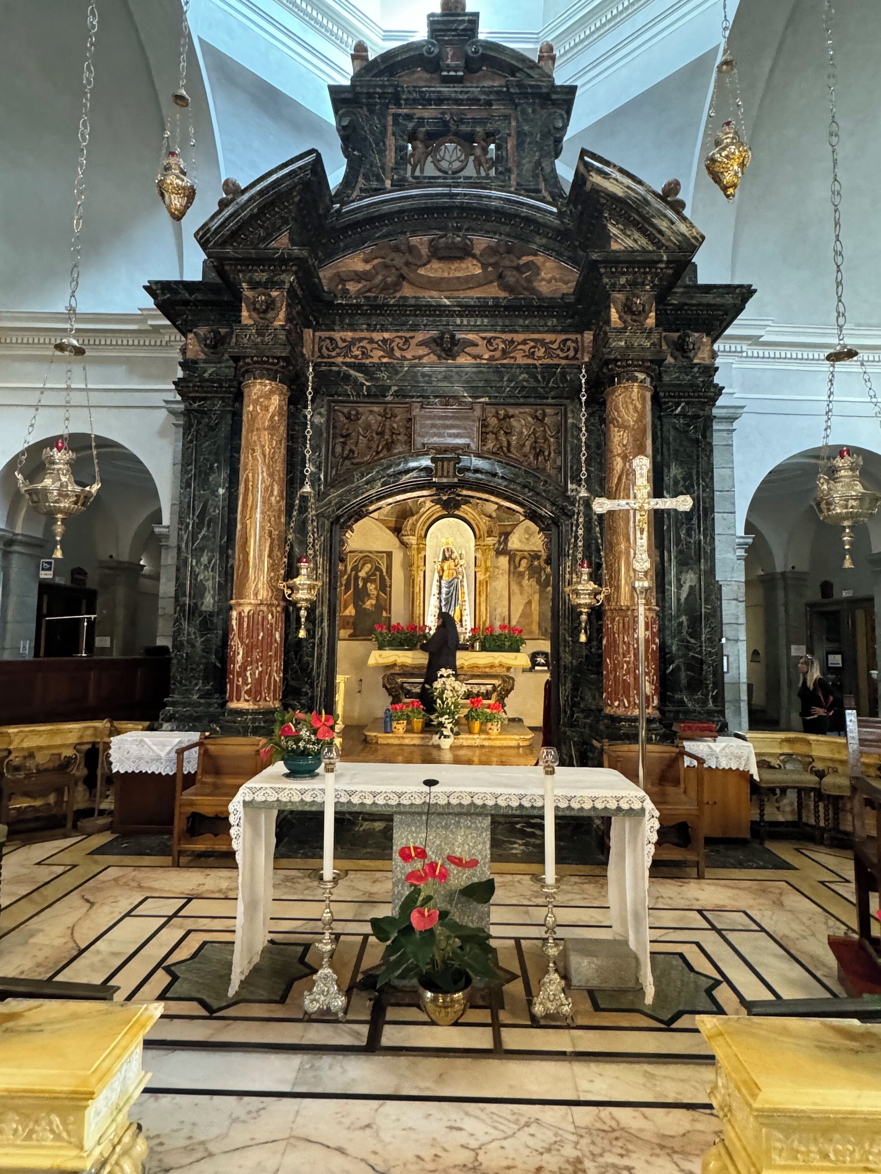 Un altar ricamente decorado con una estatua, un sacerdote y una gran cruz.