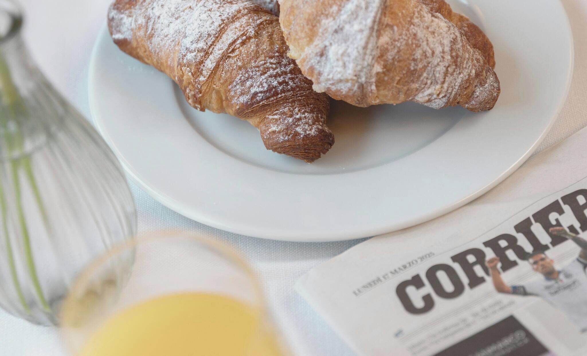 A plate with two pastries, a glass of juice, and a newspaper.