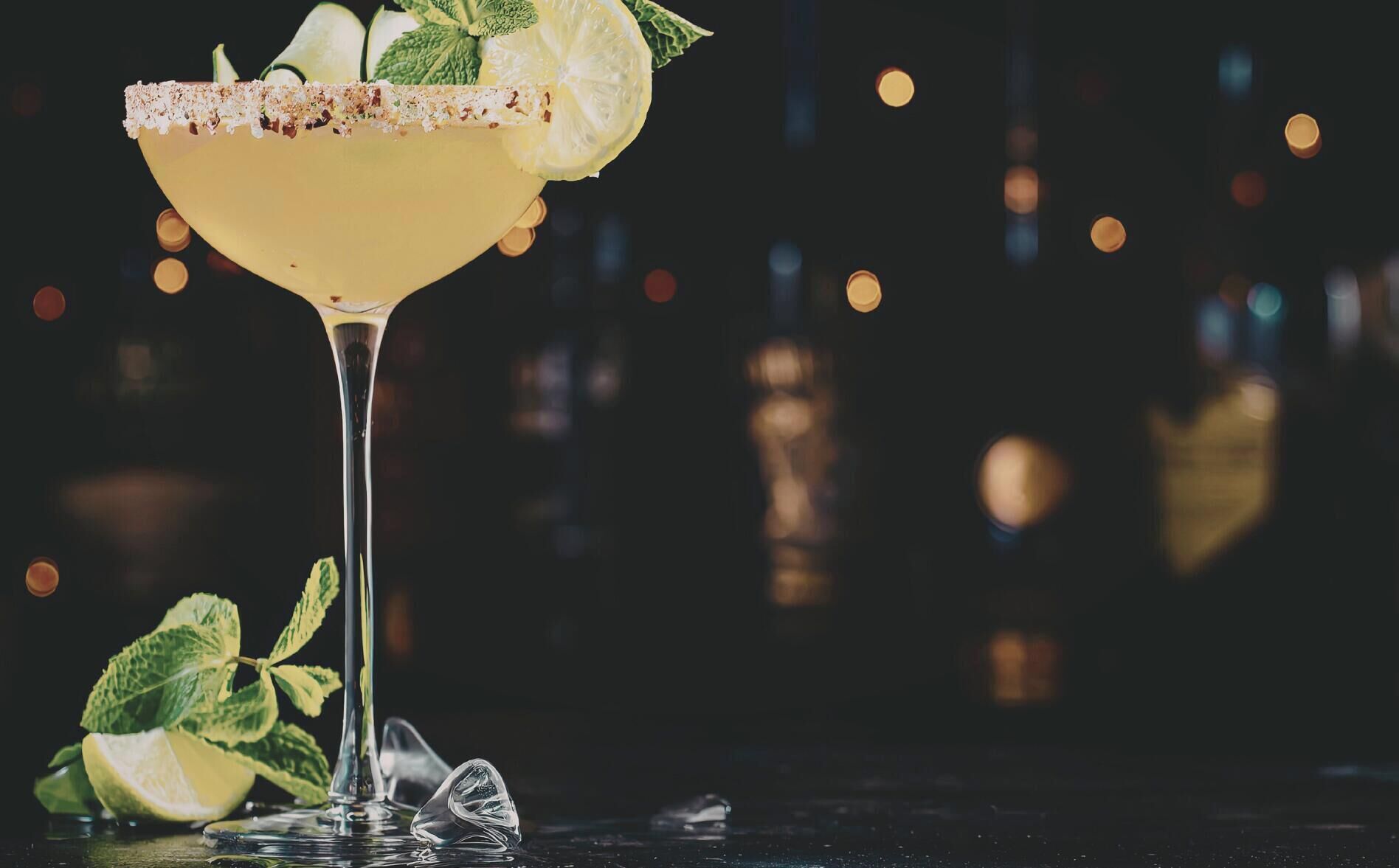 Un cocktail margarita con bordo salato, fetta di lime e guarnizione di menta.