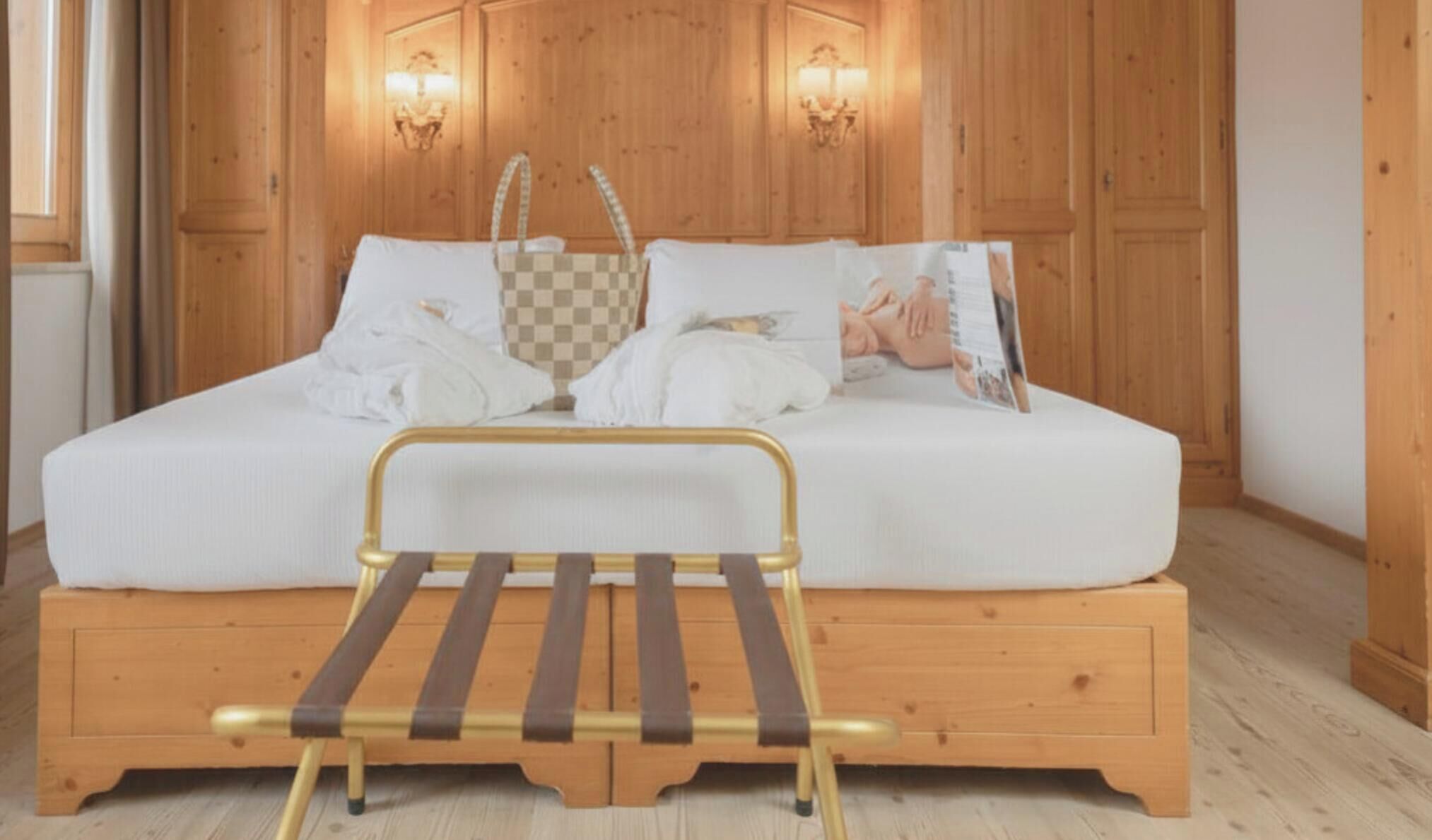 A wooden-paneled room with a bed, a small bedside table, and two wall-mounted lamps.