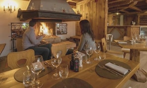 A cozy dining area with a fireplace, wooden furniture, and a table set for two.