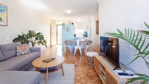 A modern living room with a grey sofa, a wooden coffee table, and a TV on a wooden stand.