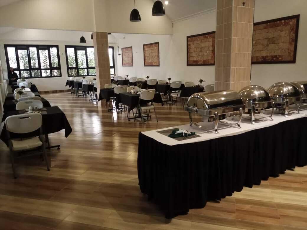 Un salón de banquetes con varias mesas, sillas y una mesa de buffet.