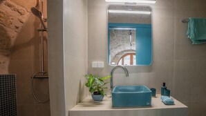 A bathroom with a modern sink, a mirror, a shower, and a potted plant. - Kritiki Spilia - Home & Spa (Prines)