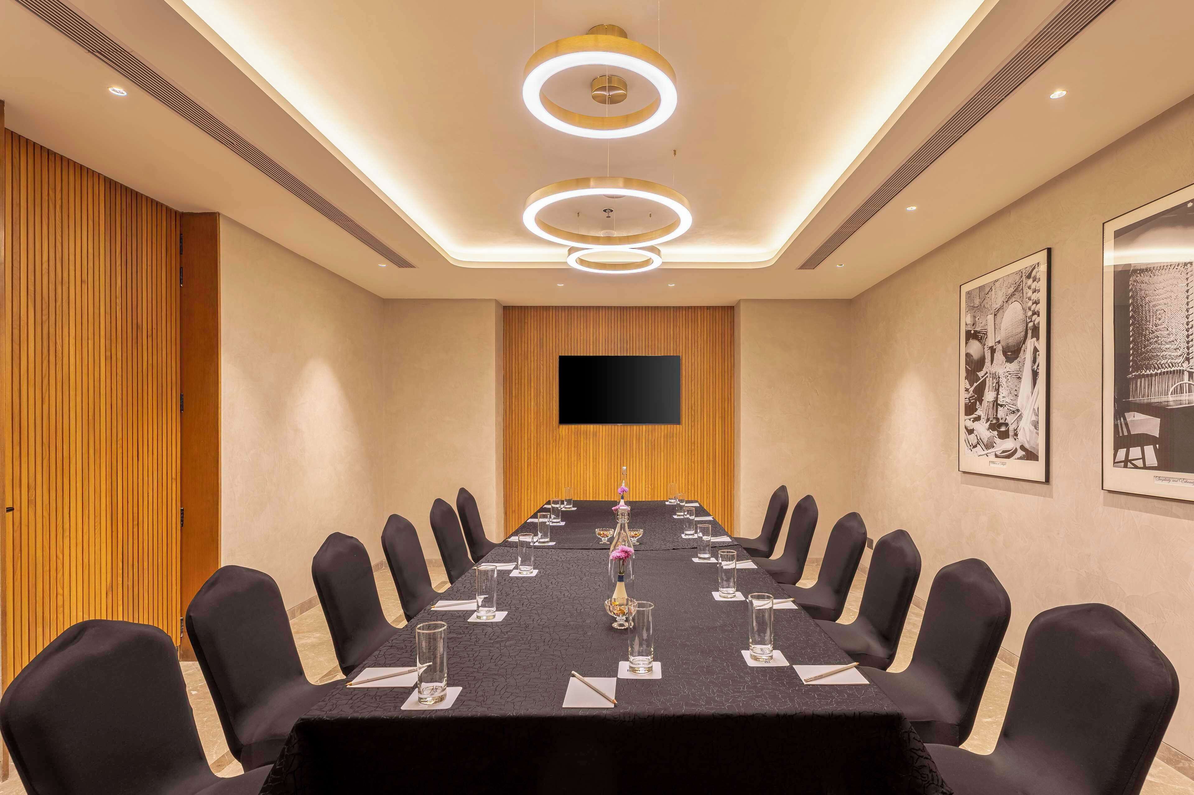 A conference room with a long table, black chairs, and a flat-screen TV on the wall.