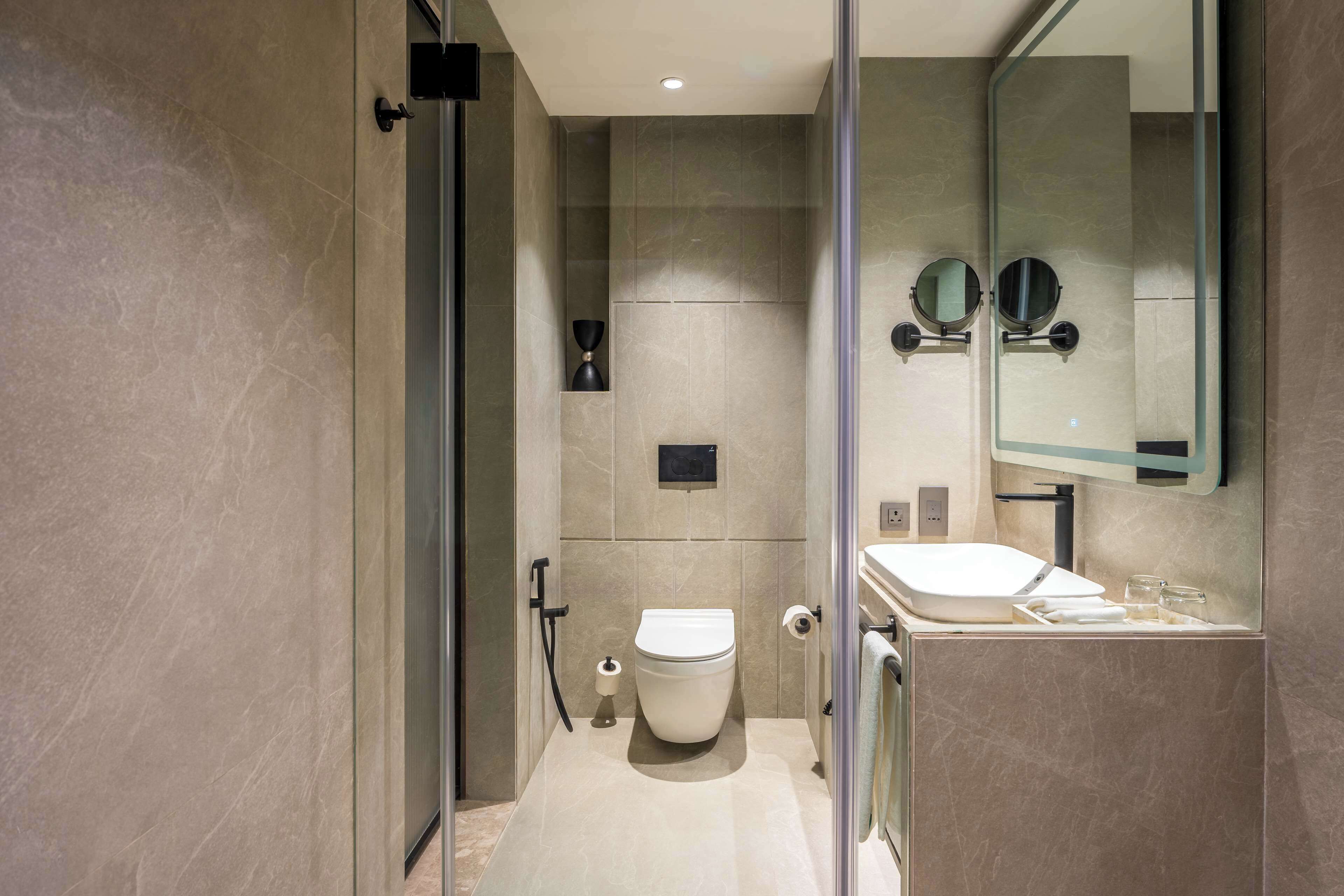 A modern bathroom with a toilet, sink, and mirror.