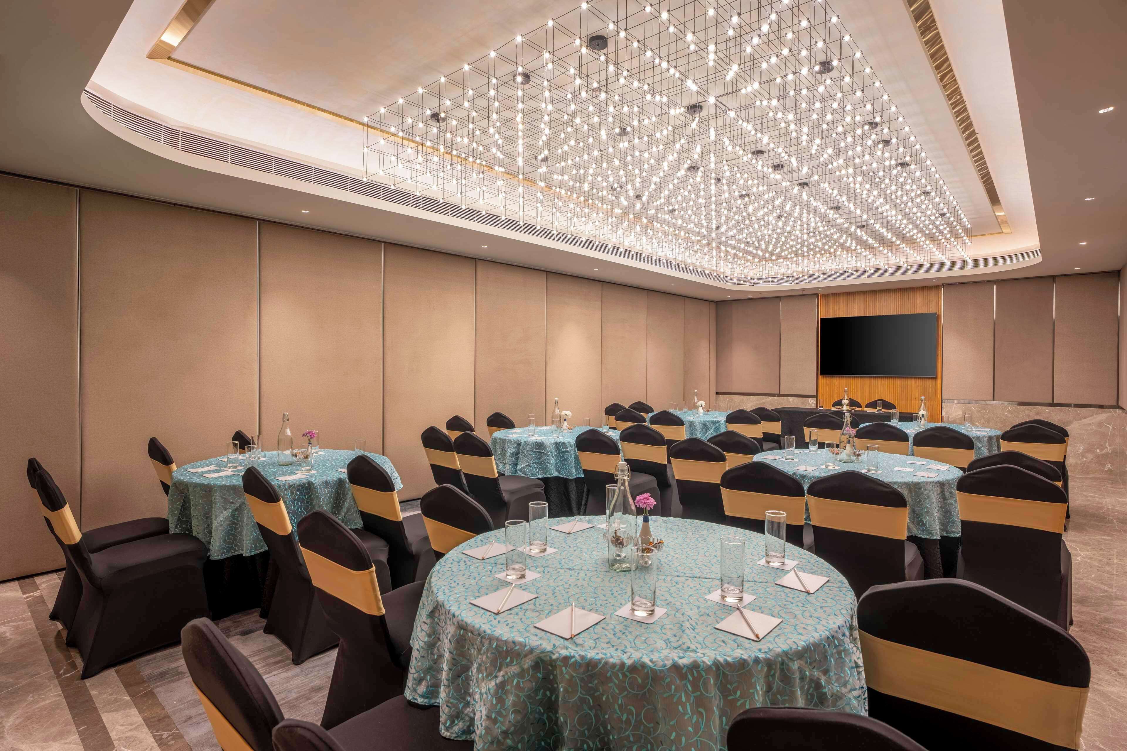 Una sala conferenze con vari tavoli, sedie e un grande lampadario.