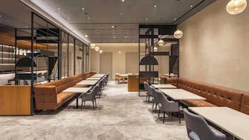 Ein modernes Restaurant mit langen Gemeinschaftstischen und gepolsterten Sitzbereichen.