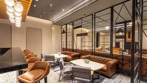 A modern lounge area with leather seating, tables, and a bar counter. - Park Inn By Radisson Jalandhar (Jalandhar)