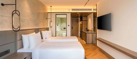 Una habitación de hotel moderna con una cama grande, un escritorio, un televisor de pantalla plana y un baño visible a través de una puerta abierta.