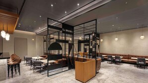A modern interior with a seating area, tables, and a partition with a wooden panel. - Park Inn By Radisson Jalandhar (Jalandhar)