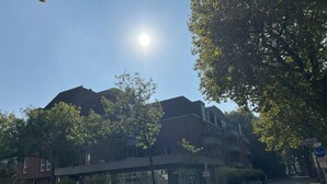 A street with parked cars, a pedestrian overpass, and multi-story buildings. - TheFairSpot - Quiet apartment right next to Nordpark / 5 min to the trade fair and arena (Düsseldorf)