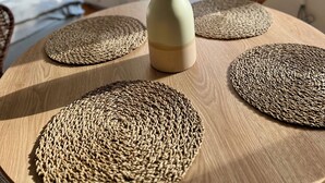 A round wooden table with woven placemats and a vase with dried grasses. - TheFairSpot - Quiet apartment right next to Nordpark / 5 min to the trade fair and arena (Düsseldorf)