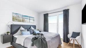 Une chambre moderne avec un lit, des tables de chevet, une chaise et une grande fenêtre avec des rideaux.