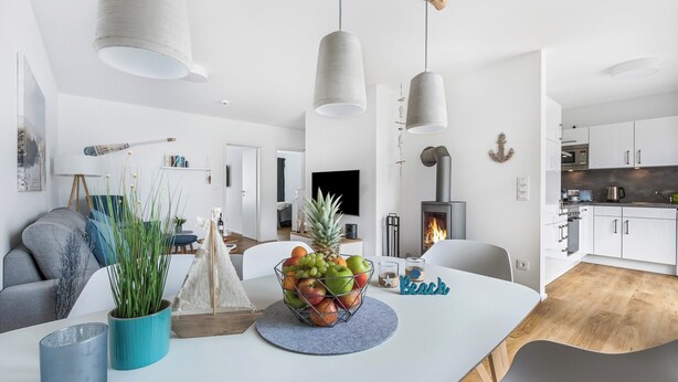 Un salon moderne avec un coin repas, comprenant une table en bois, un panier de fruits et une cheminée.