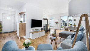 Un salon moderne avec un téléviseur à écran plat, un meuble en bois et un canapé.