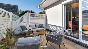 A patio with wicker furniture, a sofa, and a dining table. - Pier 12b - for 4 persons, parking space, quiet location, modern, cosy terrace (Büsum)