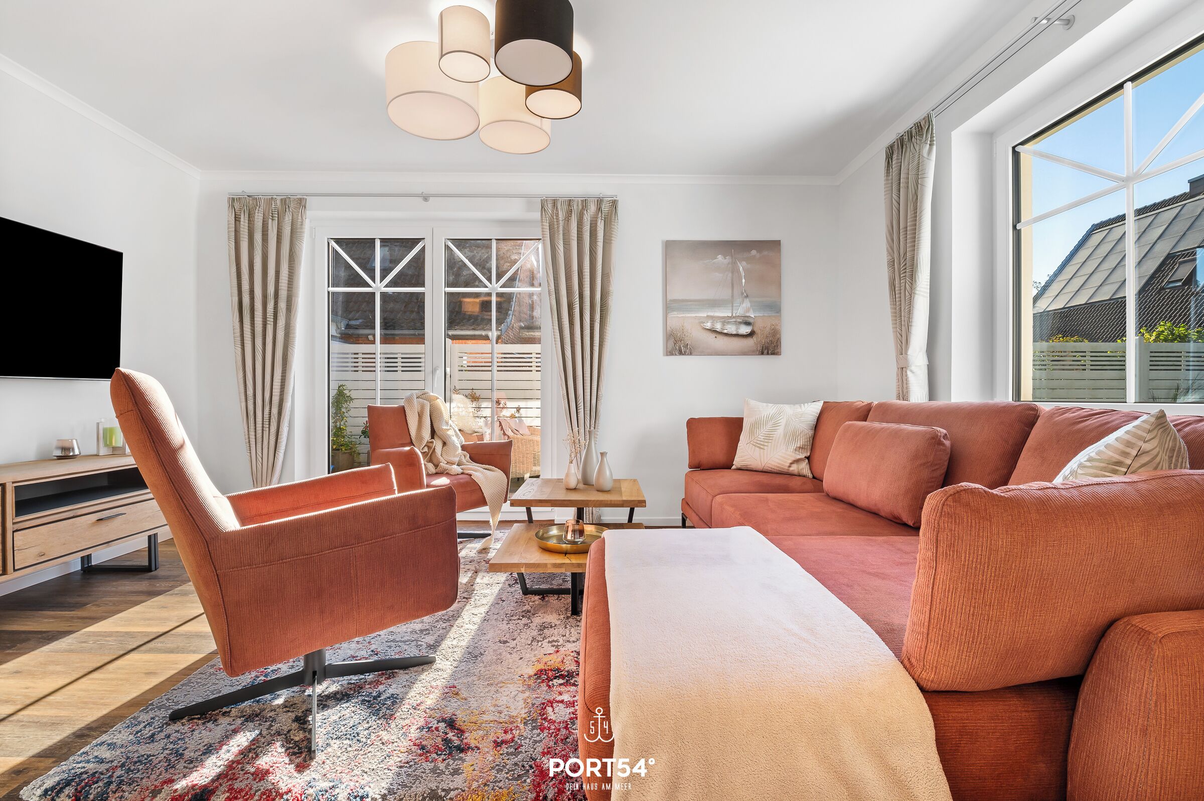 A modern living room with a sofa set, a coffee table, a TV, and a large window with curtains.