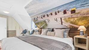A bedroom with a large bed, a view of the beach, and a wooden staircase leading to the beach. - Pier 12b - for 4 persons, parking space, quiet location, modern, cosy terrace (Büsum)